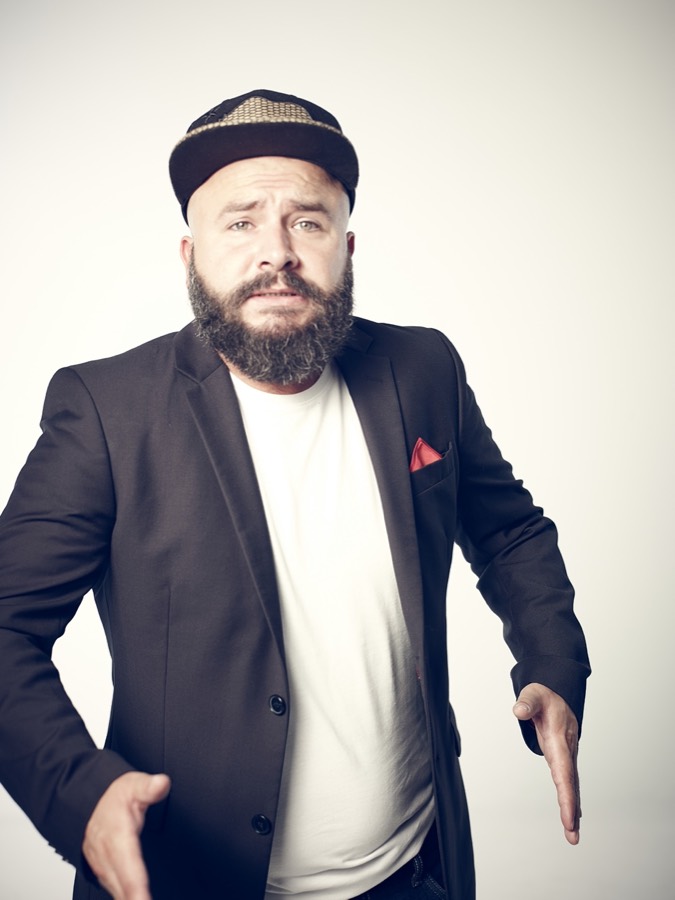 Ralf Rachbauer im Porträt mit Sakko, Einstecktuch und Mütze